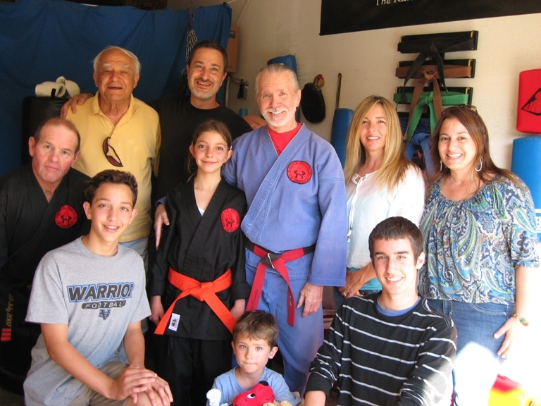 Surrounding Hannah and Mr. King, posing in the center of the photo, are, in the back row, from left to right: Black Belt Kim &ldquo;Cultivator&rdquo; Thomas, Grandpa Shamassian, Mr. Shamassian, Mrs. Shamassian, and Aunt Silva; in the front row, from left to right: Josh &ldquo;Viper&rdquo; Shamassian, Aidan and Tristan &ldquo;Raptor&rdquo; Ligtvoet. Photographer, Mrs. Ligtvoet (not pictured).