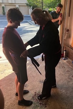 The satisfying moment of accomplishment. The donning of his Purple Belt.